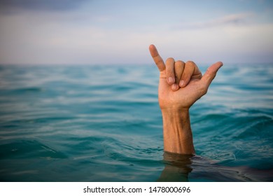 Hand Of Surfer Making Shaka (hang Loose) Sign In Tropical Blue Waters