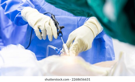 Hand of Surgeon picking up surgical instruments for doctor inside operating room in hospital.Doctor in blue uniform does minimal invasive endoscopic keyhole spine surgery.People working with light. - Shutterstock ID 2268656631