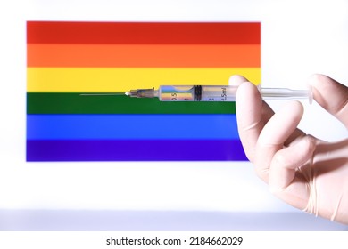 Hand In Surgical Glove Holding Syringe And Rainbow Flag In The Background