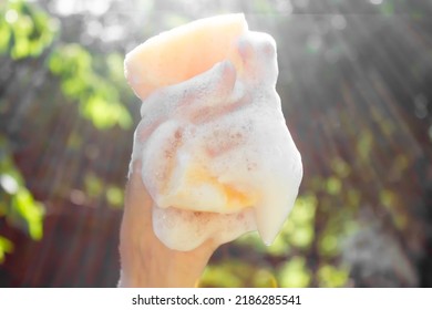 Hand Survives Washcloth With Foam. A Hand Holds A Washcloth In The Sunlight.