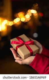 Hand in Pullover, die Geschenkbox mit Bokeh-Licht im Hintergrund zum Feiern des Weihnachtskonzepts