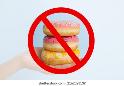 Hand with sweet donuts and prohibition sign on light background - Shutterstock ID 2162323139