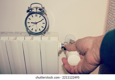 Hand Switching Off The Radiator At A Certain Time , Concept Of Energy Saving Ordinance. 