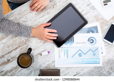A woman’s hand at a table useing a tablet.