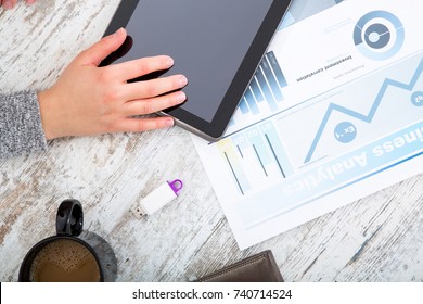 A womanâ??s hand at a table useing a tablet.