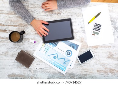 A womanâ??s hand at a table useing a tablet.