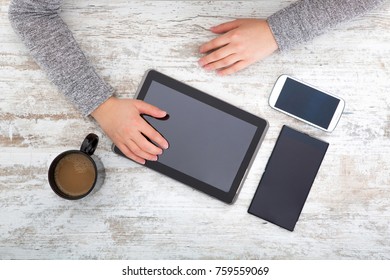 A womanâ??s hand at a table useing a tablet.