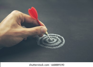 hand take a dart into the center of sketching dartboard - Shutterstock ID 668889190
