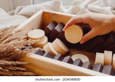 Hand take homemade soap from wooden box full of natural solid shmpoo and soaps. Quality control, delivery, batch - Shutterstock ID 2034348830