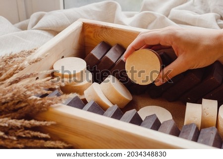Hand take homemade soap from wooden box full of natural solid shmpoo and soaps. Quality control, delivery, batch