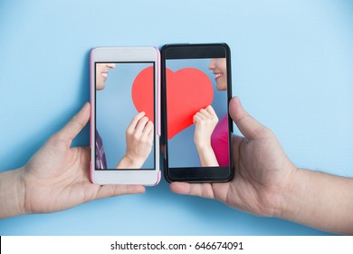 Hand Take Smart Phone With Young Couple Take Heart In Screen On Blue Background