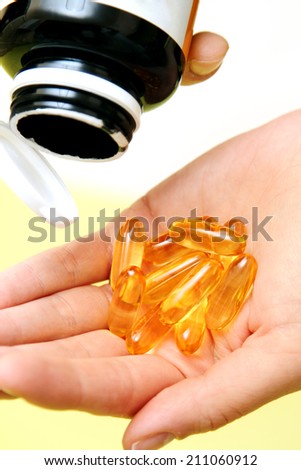 hand take vitamin Omega-3 fish oil pills on a hand