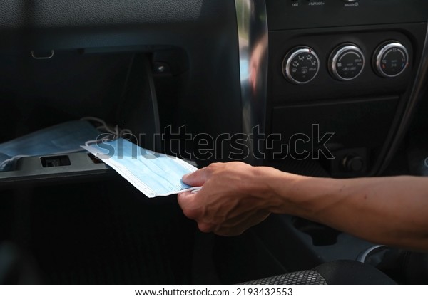 hand takes a medical mask from the glove compartment\
in the car