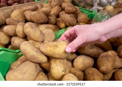 The hand takes a potato close-up. Buying potatoes and vegetables at the grocery store. - Powered by Shutterstock