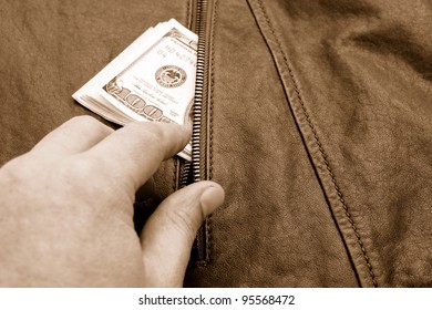 Hand taking dollars from a pocket of leather jacket.