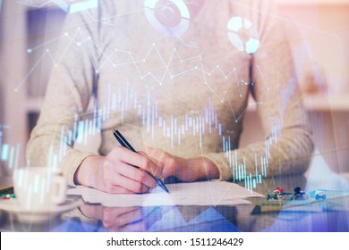 Hand taking notes in notepad. Forex chart holograms in front. Concept of research. Double exposure