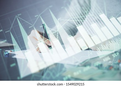 Hand taking notes in notepad. Forex chart holograms in front. Concept of research. Multi exposure