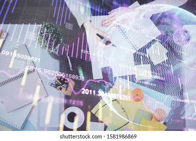 Hand taking notes in notepad. Forex chart holograms in front. Concept of research. Double exposure