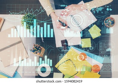 Hand taking notes in notepad. Forex chart holograms in front. Concept of research. Double exposure