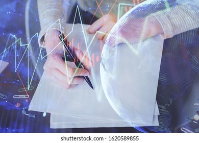 Hand taking notes in notepad. Forex chart holograms in front. Concept of research. Multi exposure - Powered by Shutterstock - Get 15% off with code: PIKWIZARD15