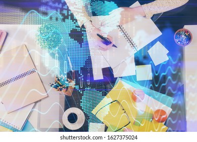 Hand taking notes in notepad. Forex chart holograms in front. Concept of research. Double exposure