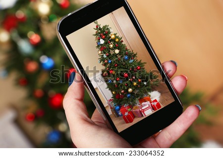 Hand taking photo of Christmas tree by smartphone
