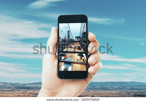 Hand taking photo of city with mobile phone. Creative\
background concept 