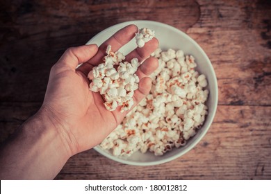 A Hand Taking Popcorn From A Large Bowl