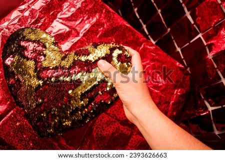 Hand taking red and golden heart cushion from table with red gift wrap