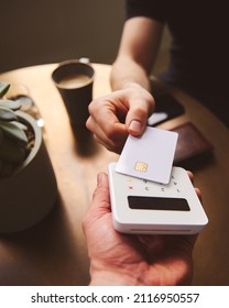 Hand Tapping A Credit Card On A Contactless Card Reader Paying For Coffee In Coffee Shop