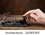 Hand tapping morse code on an antique telegraph