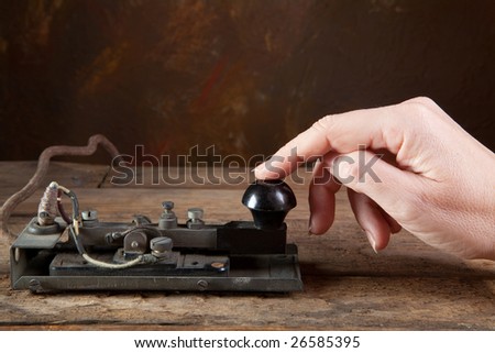 Hand tapping morse code on an antique telegraph
