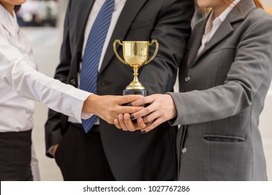 hand of Team business happy expression holding a golden trophy our success. Make winner gesture. Concept Teamwork is the best for business - Powered by Shutterstock