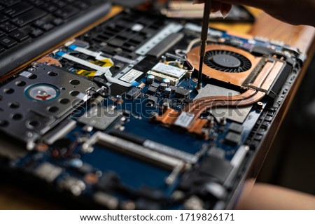 Hand technician repairing broken laptop notebook computer with a screwdriver