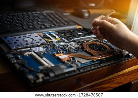 Hand technician repairing broken laptop notebook computer with a screwdriver Сток-фото © 