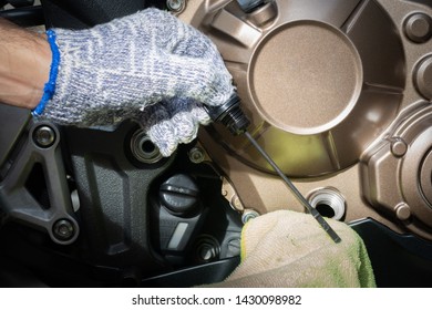 Hand of technician wearing cloth gloves check lubricant engine oil level motorcycle bigbike. maintenance motorcycle concept in garage or check before you travel.