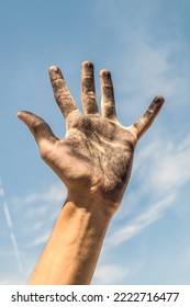 The hand of a teenager is stained with soot against the sky - Shutterstock ID 2222716477