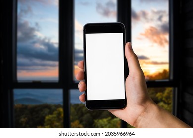 Hand That Are Holding A Black Phone With A Blank White Screen In The Morning Light Of An Air Residence.