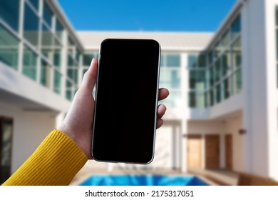 Hand That Are Holding A Black Phone With A Blank  Screen In The Morning Light Of An Air Residence.