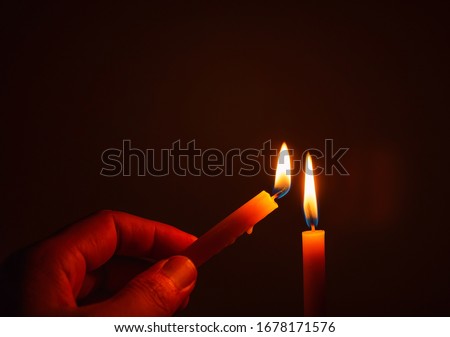 
The hand that is lighting candles in the dark with burning candles shining the light at night Design for the background, Burning candles on black background, Candle in hand, Candles in the dark.