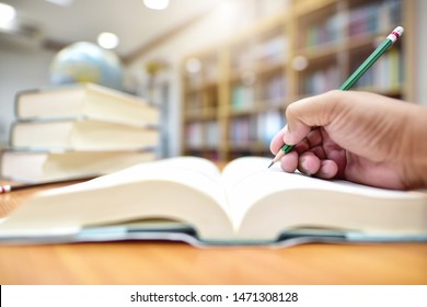 A Hand That Is Note An Book On Study Desk In Library Room. Education Or Academic Concept Picture Image Of Teaching And Learning Materials In High School, College Or University Campus. Selective Focus