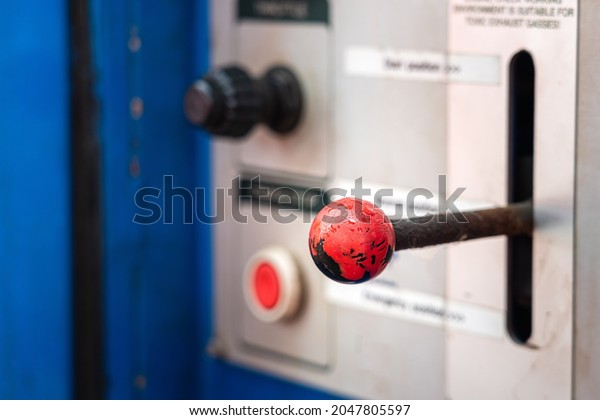 A hand throttle for controlling speed of the\
hydraulic power pack engine, with blurred background of control\
panel part. Industrial equipment object photo. Selective focus at\
the handle part.