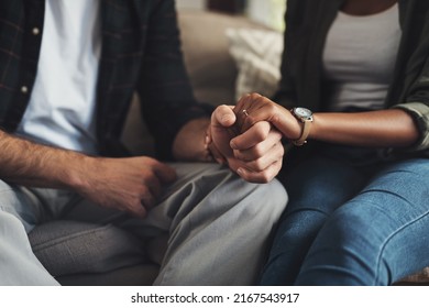 Hand in hand through it all. Shot of an unrecognizable couple holding hands while sitting on a sofa at home. - Powered by Shutterstock