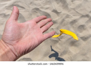 Hand Throwing Banana Peel On The Beach