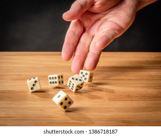 Hand throwing dice in front of a black background. - Shutterstock ID 1386718187
