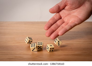 Hand throwing dice in front of a grey background. - Shutterstock ID 1386718163