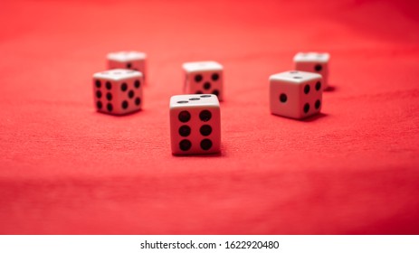 Hand Throwing Dice, Hoping For The Best Odds. Six Dice On Red Background