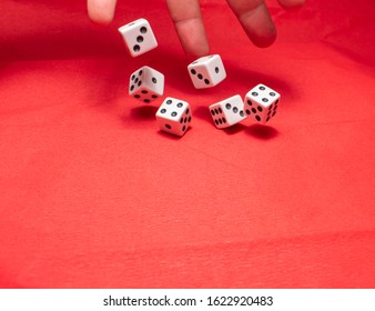 Hand Throwing Dice, Hoping For The Best Odds. Six Dice On Red Background