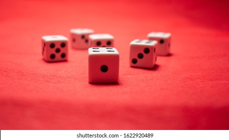 Hand Throwing Dice, Hoping For The Best Odds. Six Dice On Red Background