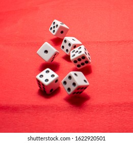 Hand Throwing Dice, Hoping For The Best Odds. Six Dice On Red Background